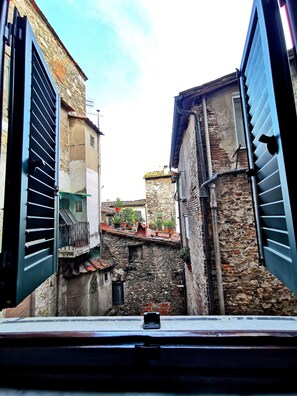 A narrow street with stone buildings, a staircase, and a metal gate.