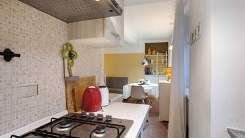 Een koelkast, een kookplaat, kookgerei, borden en bestek