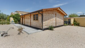 A wooden cabin with a sloped roof, a gravel driveway, and a potted plant in the foreground.