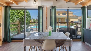 A dining area with a table, chairs, and a view of a pool and house.