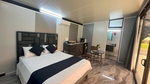 Una camera d'albergo con un letto, una scrivania, una sedia e un tavolino.