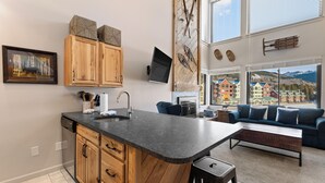 A modern kitchen with wooden cabinets, a granite countertop, and a large window overlooking a scenic mountain view. - Ew1447-1 (Keystone)