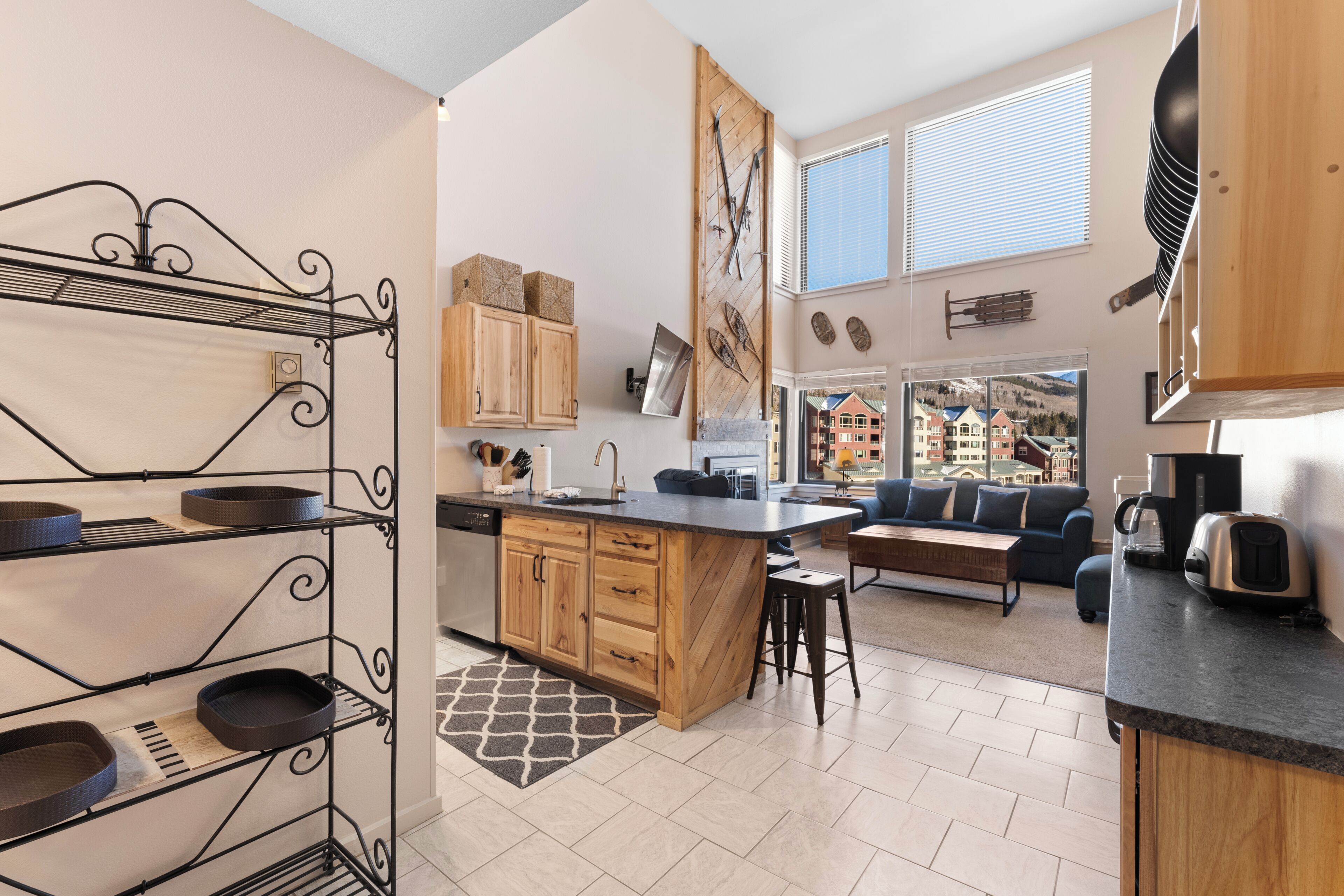 A modern kitchen with a central island, wooden cabinets, and a black metal rack.