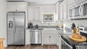 A modern kitchen with stainless steel appliances, white cabinetry, and a granite countertop. - Stoked by Avantstay Gulf View, Steps to the Beach (Santa Rosa Beach)