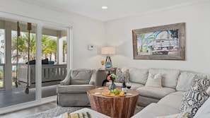A living room with a sofa, a coffee table with snacks, a lamp, and a painting on the wall. - Stoked by Avantstay Gulf View, Steps to the Beach (Santa Rosa Beach)