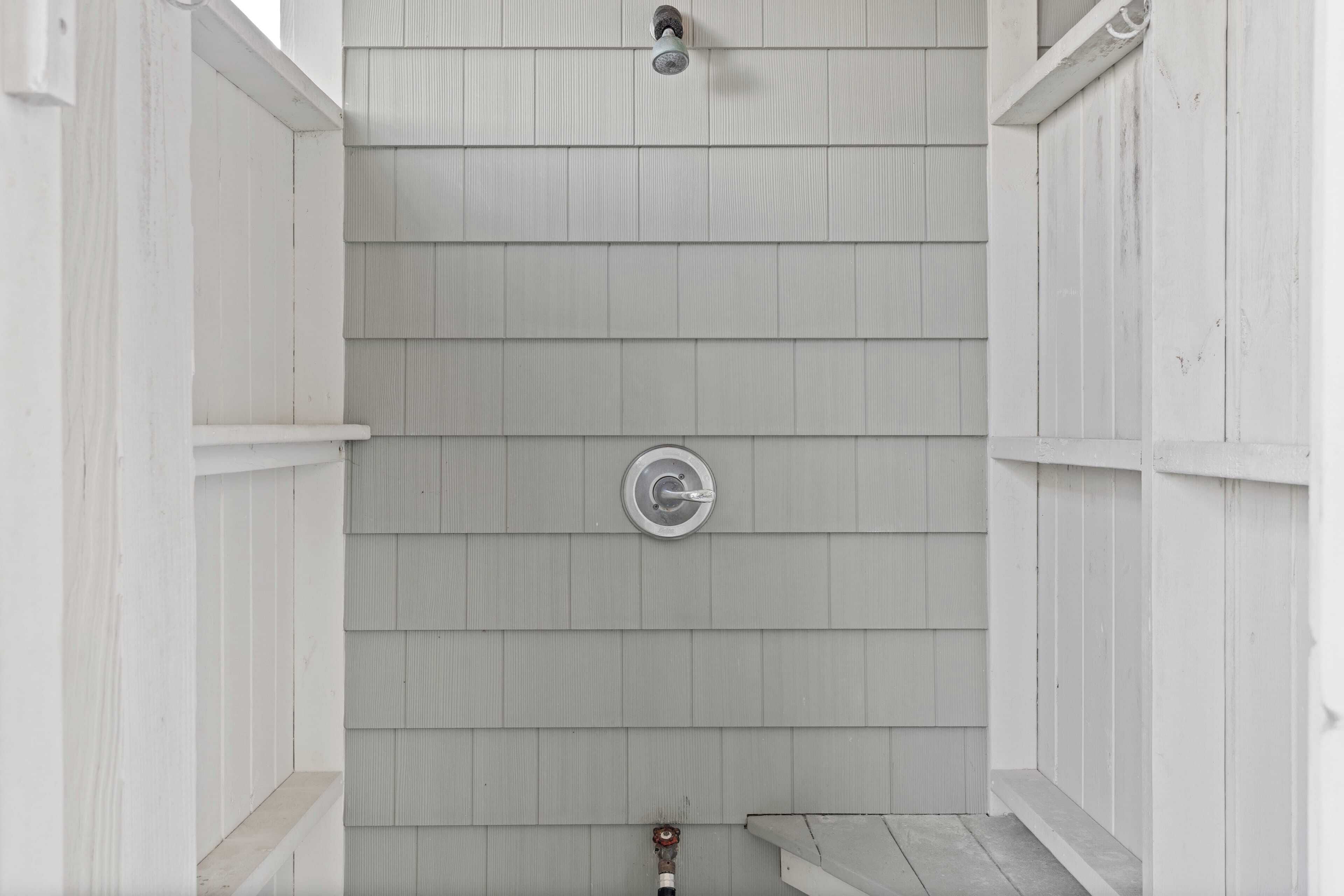 A white wooden shower enclosure with a metal showerhead and a control valve.