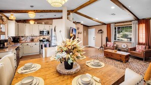 A spacious living area with a wooden dining table set for four, a sofa, and a coffee table. - JT Ranch: Observatory Sky Deck & Heated Cowboy Pool (Joshua Tree)