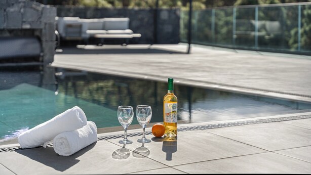 A poolside area with a bottle of alcohol, two glasses, and rolled towels. - 'Buena - Vista' with Sea Views, Private Pool and Wi-Fi (La Guancha)