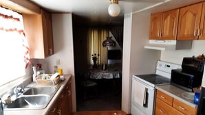 A compact kitchen with wooden cabinets, a white stove, a microwave, and a sink.