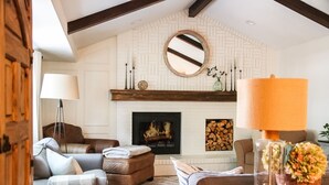 Ein gemütliches Wohnzimmer mit Kamin, Ledersofas, einem Holztisch und einem großen Spiegel an der Wand.