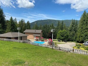 Un hôtel doté d’une piscine, d’un espace extérieur aménagé et offrant une vue sur une montagne boisée.