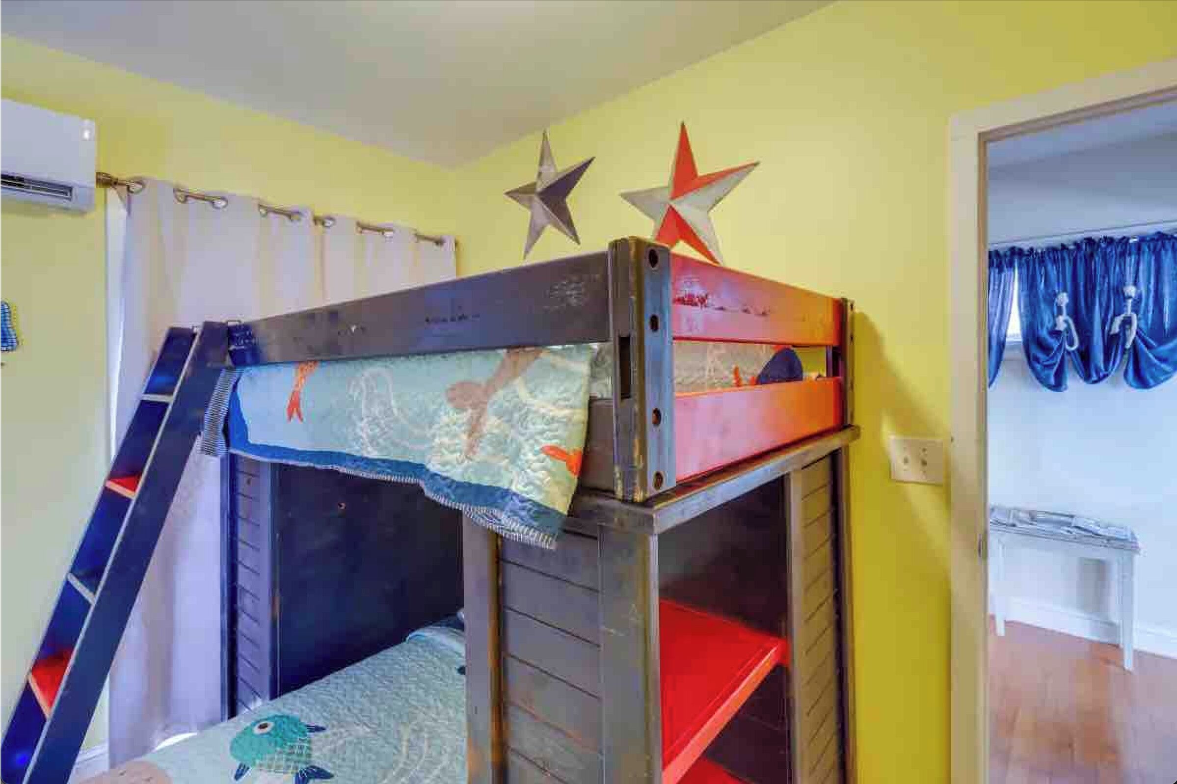 A bunk bed with a ladder, a star decoration, and a curtain.