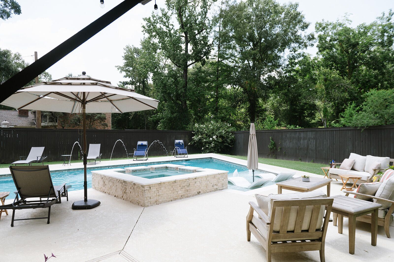 A backyard with a swimming pool, lounge chairs, and a wooden deck.