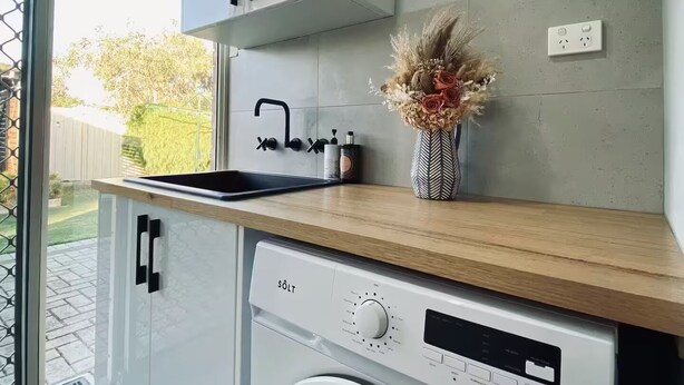 A compact kitchen with a built-in washing machine, a sink, and a small countertop. - Cosy Home near SValley & Airport (Ashfield)