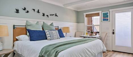 A bedroom with a large bed, a bedside table, a chair, a window, and a door.