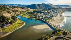 An aerial view of a coastal town with a river, a bridge, and a beach.