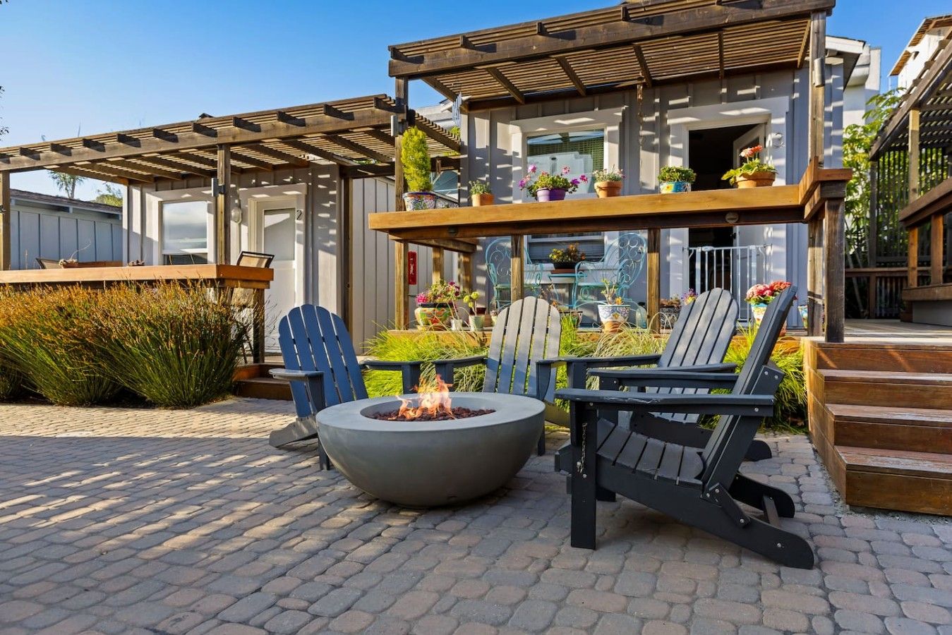 Een terras met een vuurkorf, Adirondack-stoelen en een pergola.