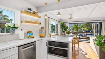A modern kitchen with white cabinetry, a built-in oven, and a dining area with a wooden table and chairs.