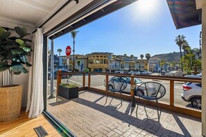 Een balkon met uitzicht op een straat, een stopbord en een gebouw met een bord waarop staat 'WINE TASTING'.