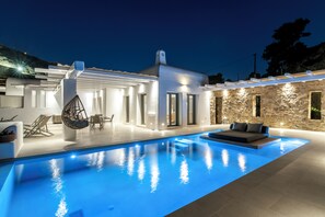 Un área de piscina moderna con una zona de estar integrada y un muro de piedra.