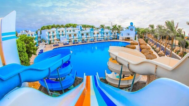 A resort with a large swimming pool, multiple water slides, and a row of palm trees. - HRG Hurghada Hotel Apartments Aqua park-By MAMO (Red Sea Governorate)