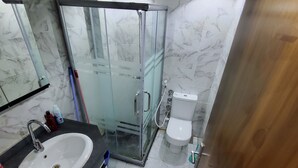 Une salle de bain avec une douche à parois de verre, un lavabo blanc et des toilettes.