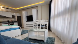 A modern living room with a sofa, a glass coffee table, and a dining area with chairs. - HRG Hurghada Hotel Apartments Aqua park-By MAMO (Red Sea Governorate)