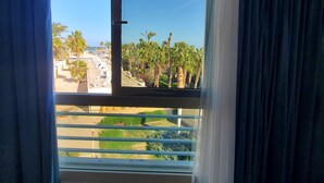 A room with a large window, curtains, and a view of palm trees and buildings. - HRG Hurghada Hotel Apartments Aqua park-By MAMO (Red Sea Governorate)