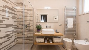Un baño moderno con cabina de ducha de vidrio, tocador de madera y bañera independiente.