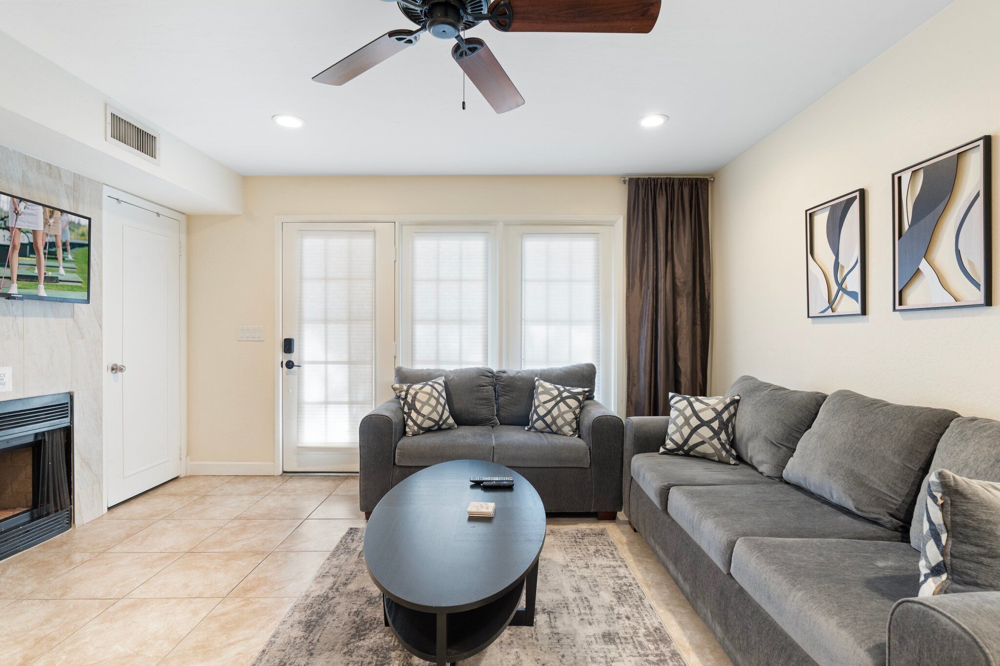 A living room with a grey sofa, a black coffee table, and a ceiling fan.
