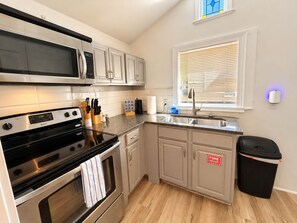 Een moderne keuken met roestvrijstalen apparatuur, een raam met zonwering en een afvalbak.