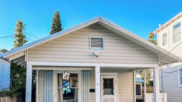 A single-story house with a porch, a small garden, and a visible garage door.
