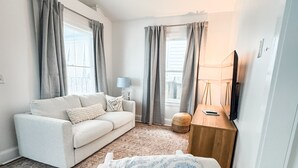 A modern living room with a white sofa, a wooden coffee table, and a patterned throw blanket.