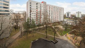 A high-rise residential building with multiple balconies, a parking area, and a playground. - Metro Wierzbno Deluxe Apartment (Warszawa)