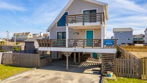 Een gebouw met twee verdiepingen, een balkon, een bord met ‘Coastal Carolina Vacation and Suites’ erop en het nummer 125 op de gevel.