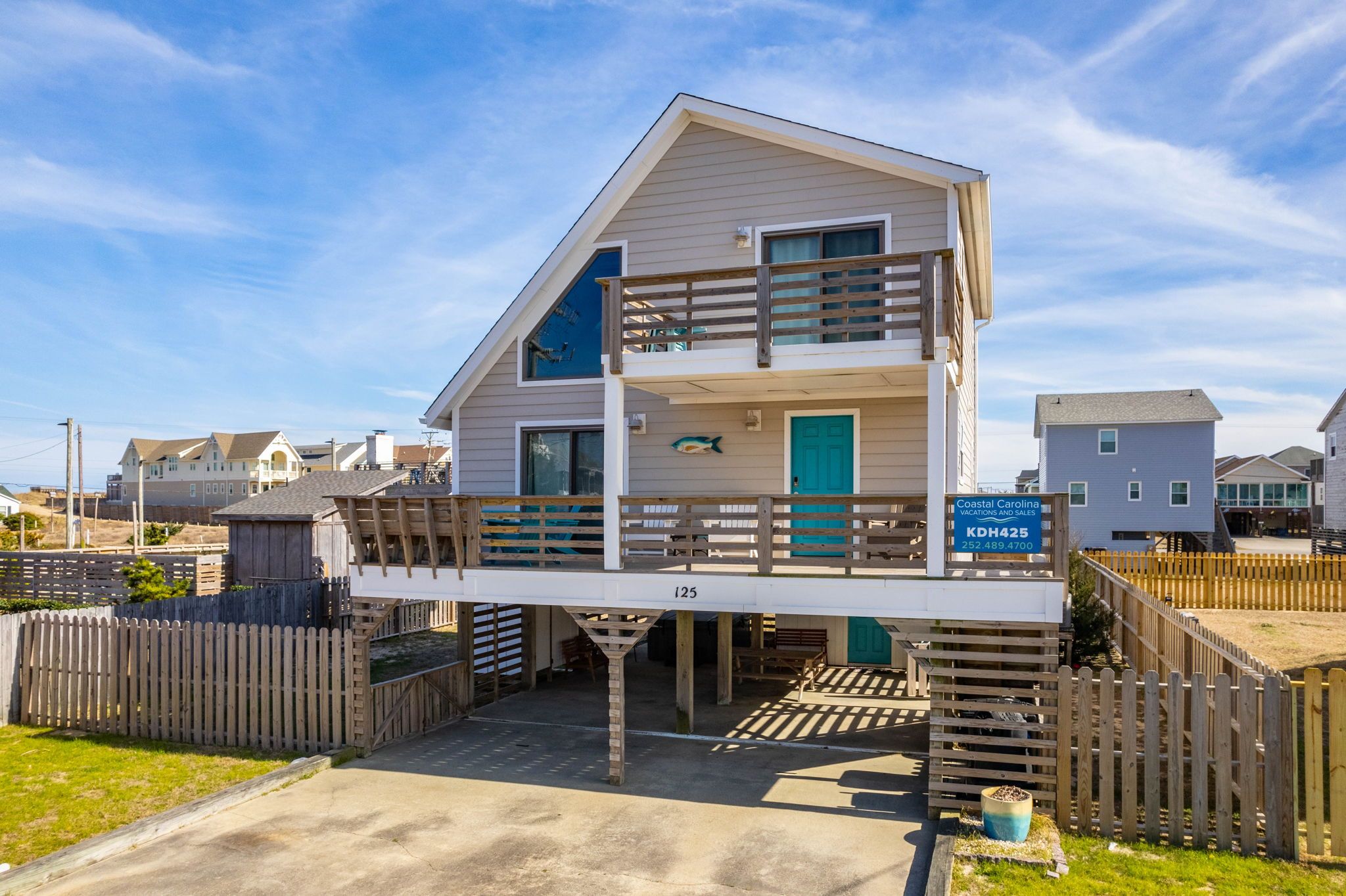 A two-story building with a balcony, a sign indicating Coastal Carolina Vacation and Suites, and a number 125 on the front.