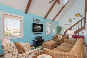 A living room with a TV, two sofas, a coffee table, and a staircase. - Kill Devil Hills 425: Oceanside, Pet Friendly, Hot Tub, Close to Beach Access (Kill Devil Hills)