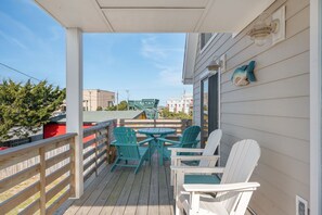 A covered outdoor area with a wooden deck, a table, and chairs. - Kill Devil Hills 425: Oceanside, Pet Friendly, Hot Tub, Close to Beach Access (Kill Devil Hills)