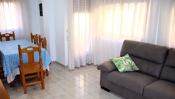A living room with a sofa and a dining table with chairs. - Los Pescadores playa LEK (Peñiscola)