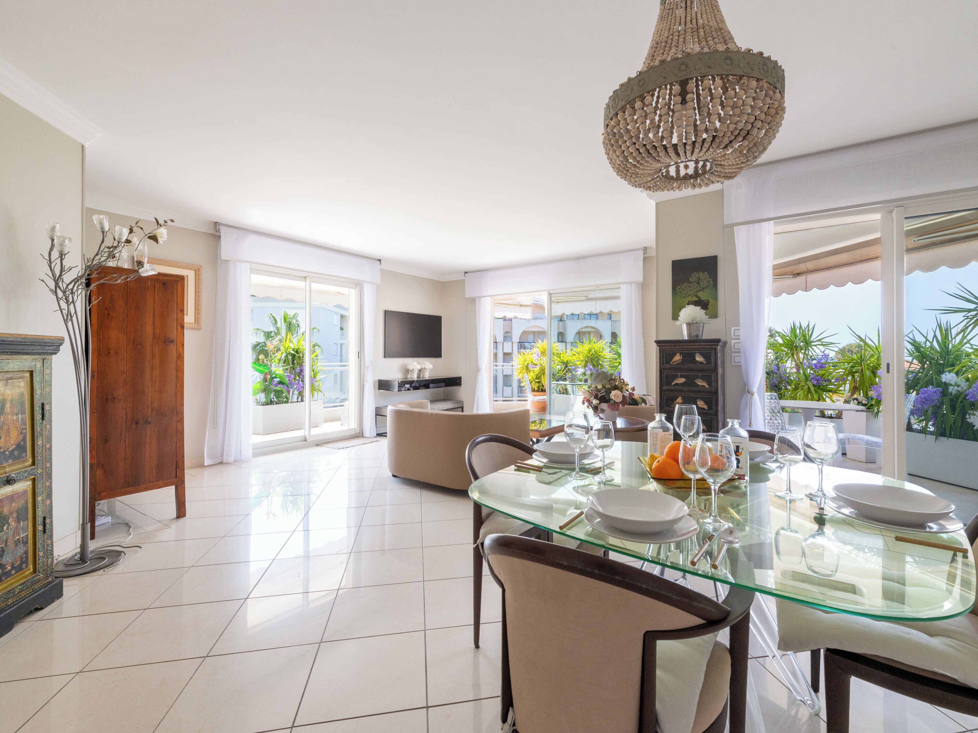 A dining area with a glass table, chairs, and a chandelier.