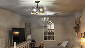 Un accogliente soggiorno con un tavolo da pranzo in legno, un divano grigio, un televisore e una lampada a sospensione decorativa.