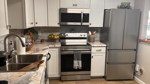 Una cucina moderna con mobili bianchi, elettrodomestici in acciaio inossidabile e pavimento in legno.