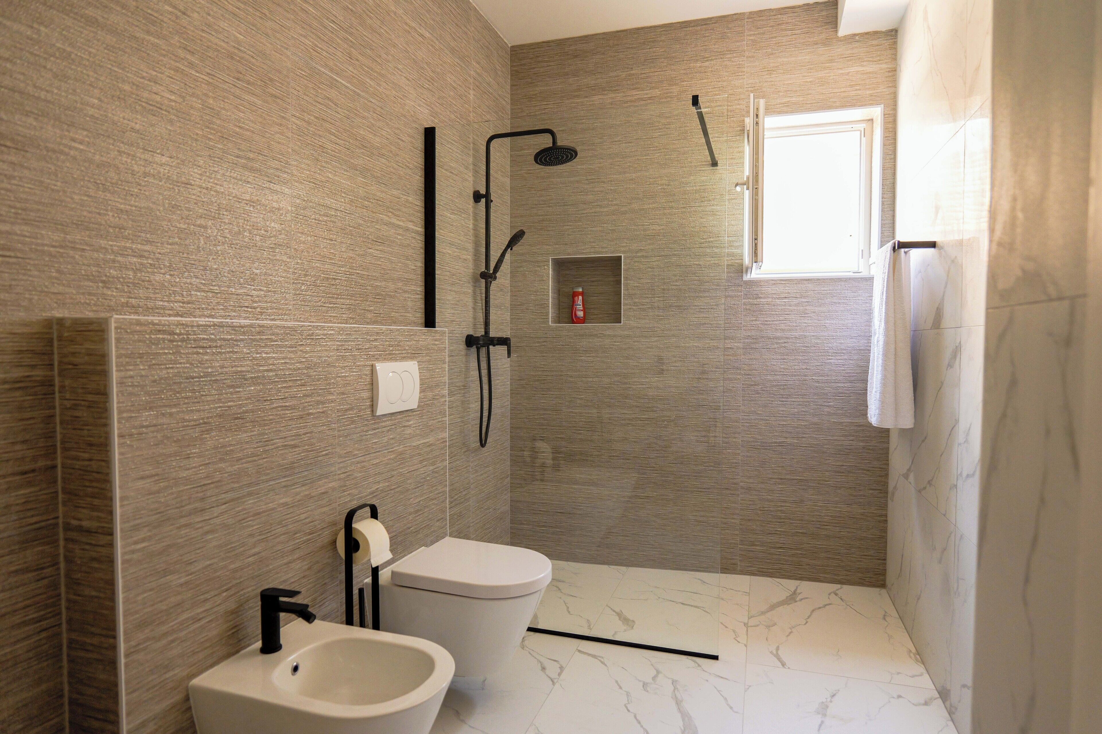 A modern bathroom with a shower, toilet, and bidet.