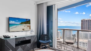 Ein modernes Hotelzimmer mit großzügigem Balkon, einem Flachbildfernseher, einem Schreibtisch und einer gemütlichen Sitzecke.