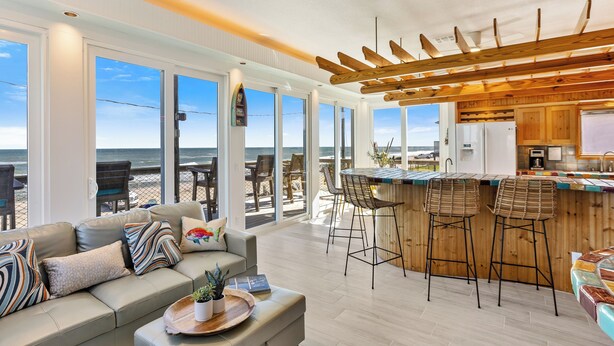 Una cocina moderna con barra de madera y amplios ventanales con vistas a la playa.