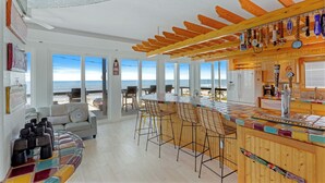 Cocina frente a la playa con barra, ventanas amplias y vista al océano.