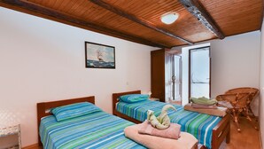 A bedroom with two beds, a wooden ceiling, a window, and a chair.