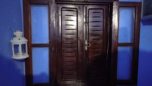 A dark wooden door with a window, a white lantern, and a blue wall. - CASA DAOUED APRT B (CHEFCHAOUEN)