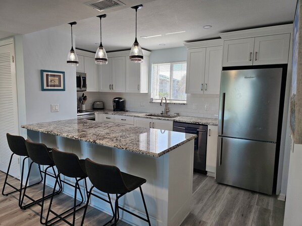 A modern kitchen with a large island, stainless steel appliances, and pendant lighting.
