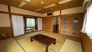 A traditional tatami mat room with a wooden table, sliding doors, and a view of the outdoors. - kinasse (Yamaga)